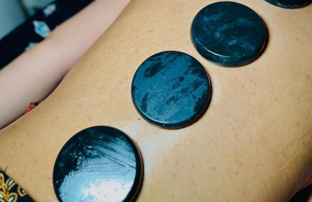 Tiga batu panas hitam di atas belakang pelanggan, beralas kain batik