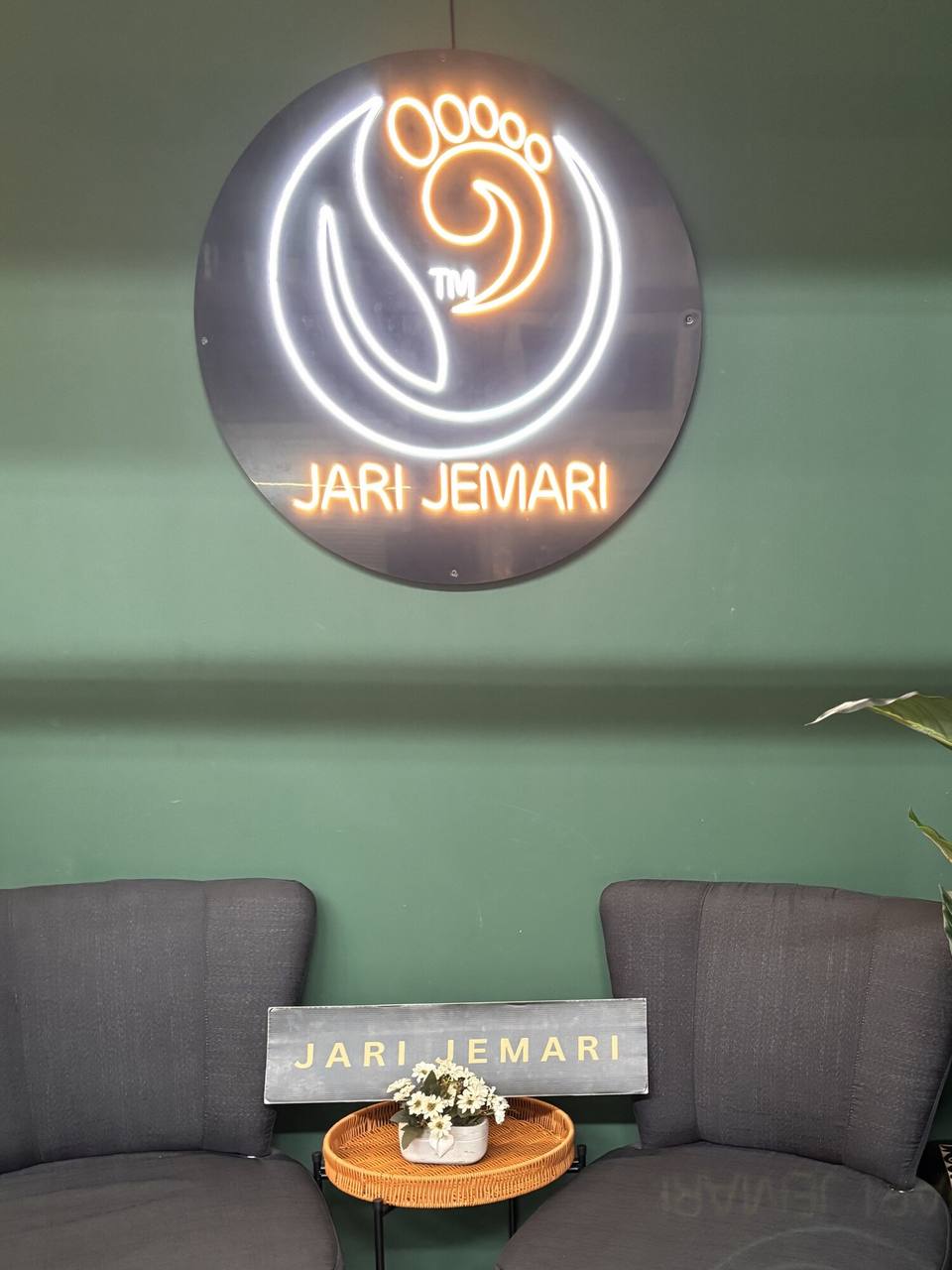 Papan neon Jari Jemari menyala di dinding hijau ruang menunggu