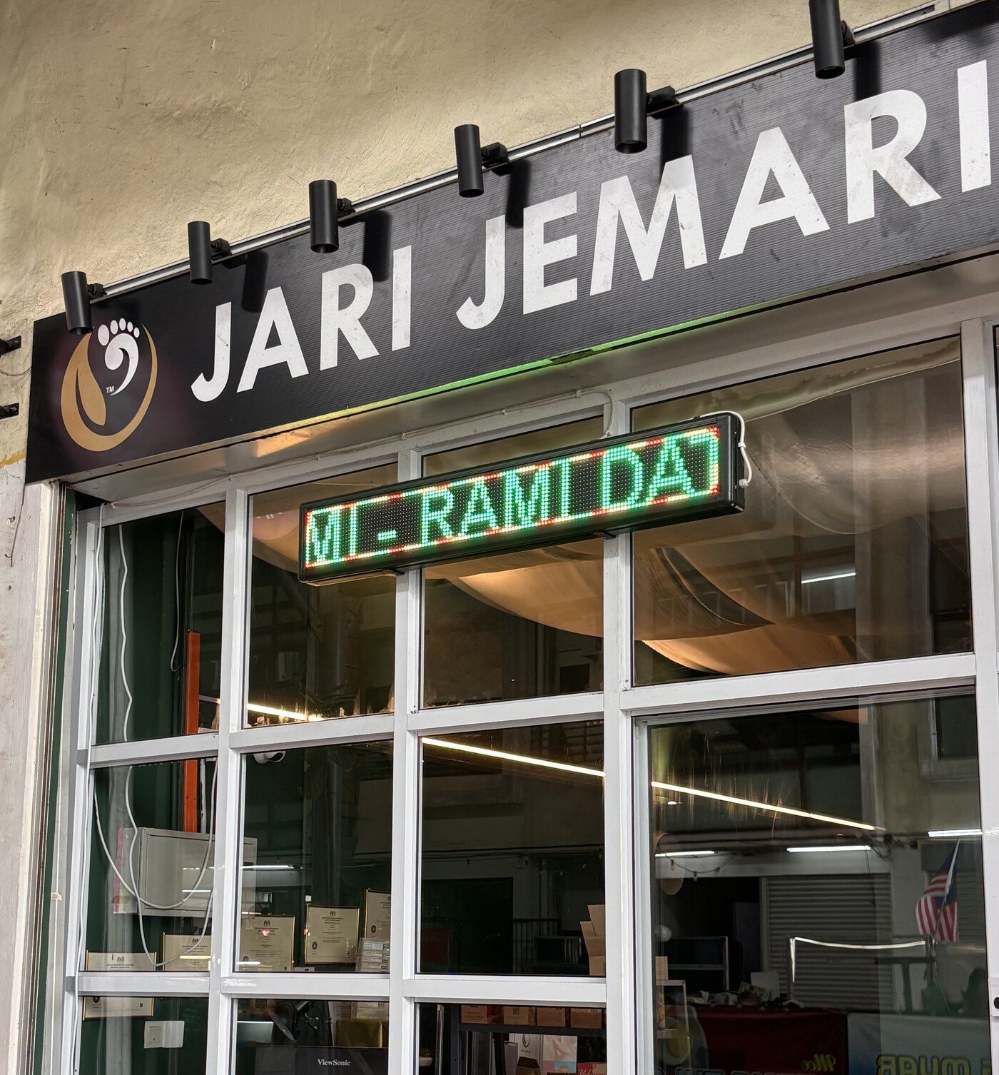 Papan tanda hitam JARI JEMARI dengan logo emas di atas pintu kaca kedai